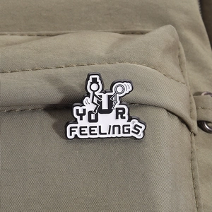 Macro shot of minimalist black and white metal badge with stickman and YOUR FEELINGS text