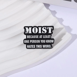 Minimalist black enamel pin with white text MOIST satire quote on wave display