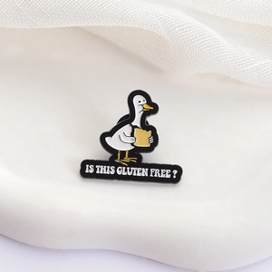 Détail d'un pin's émaillé montrant un canard avec toast et texte sans gluten