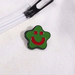 Macro detail of a green star enamel brooch featuring a smiling face on canvas bag