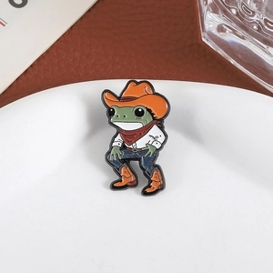 Gros plan détaillé d'une épingle émaillée grenouille cowboy sur une assiette blanche en céramique