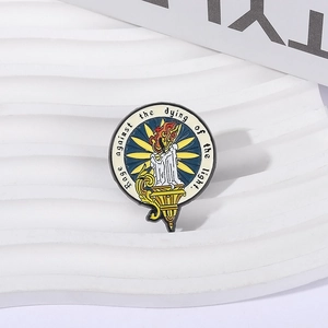 Détail d'un pin's rond en émail avec une bougie allumée et une citation inspirante