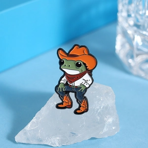 Vue détaillée de la broche émaillée grenouille cowboy sur un support en cristal