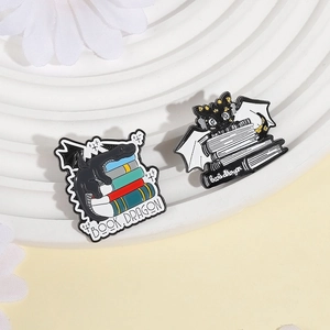 Lot de pin's dragon de livre en émail avec livres colorés sur plateau décoratif