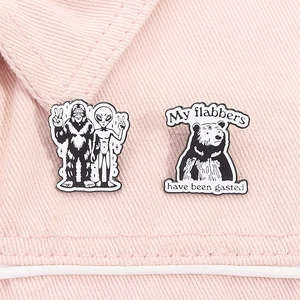 Détail de pin's en émail avec motifs extraterrestre et ours sur tissu denim rose