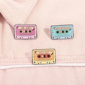 Close-up of three retro colorful enamel cassette tape pins with chill and sad vibes