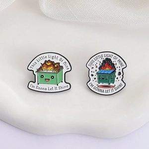 Cartoon burning trash can enamel pins with 'This Little Light Of Mine' quote on white tray