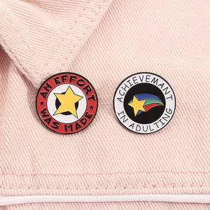 Detailopname van grappige emaille speldjes op roze denim met ster en regenboogpatroon
