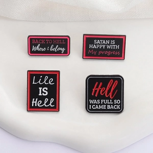 Macro shot of gothic enamel pins featuring red 'BACK TO HELL' text on black metal