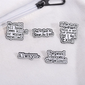 Detail of five enamel pins with movie quotes pinned on a white canvas bag surface