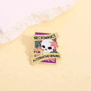 Skull and pink flower enamel pin with Necromancy text on warm stone background