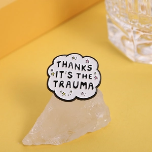 Cloud-shaped enamel badge featuring "THANKS IT'S THE TRAUMA" text with colorful stars