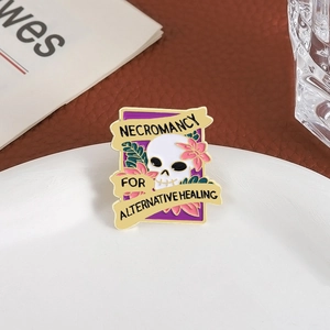 Macro view of purple enamel skull pin with Necromancy text on a white plate