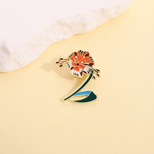 Detail of tiger head lily enamel brooch with gold plating on a warm stone display
