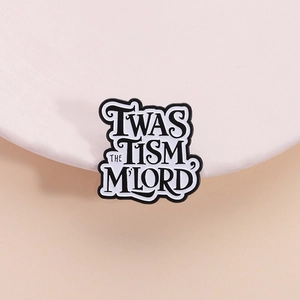 Dettaglio macro della spilla in smalto con scritta artistica 'TWAS THE TISM M'LORD' bicolore