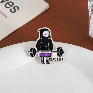 Cartoon skeleton weightlifting enamel pin with Dead Lift slogan on a white tray