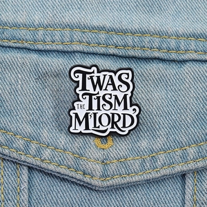 Twas The Tism My Lord black enamel pin badge pinned on a denim jacket pocket