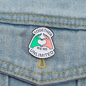 Enamel heart hand pin with Together We Are Unlimited quote on denim jacket