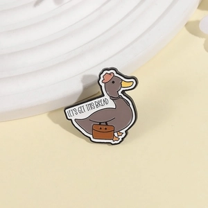 Détail du pin's en émail canard avec texte 'LET'S GET THIS BREAD' et mallette