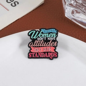 Emaille-Brosche mit farbigem 'STRONG Women' Spruch auf schwarzem Metall-Hintergrund