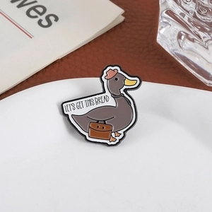 Cute duck enamel pin with 'Let's Get This Bread' text on a stylish white tray