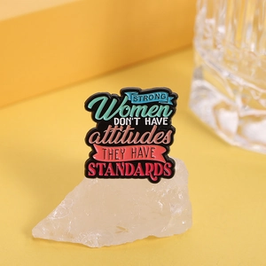 Close-up of enamel pin with Strong Women Don't Have Attitudes They Have Standards text