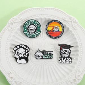 Set of five Karl Marx enamel pins with pop art designs on a white ceramic plate