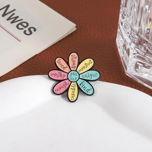 Detail of colorful daisy enamel brooch with inspirational words on a ceramic plate