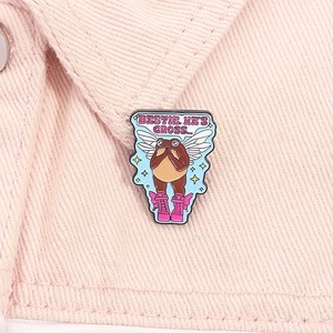 Detail of whimsical enamel frog pin with Bestie He's Gross text on a denim collar