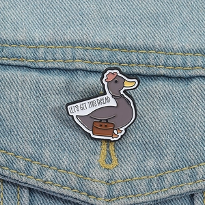 Cartoon duck enamel pin with Let's Get This Bread quote on blue denim fabric