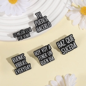 Set of minimalist black enamel brooches with white Spanish motivational quotes on white stand