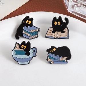 Set of four creative black cat enamel pins featuring kittens reading on colorful books