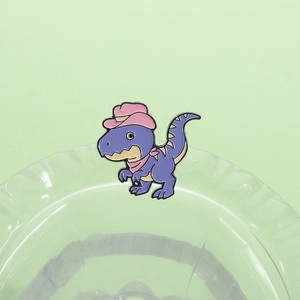 Dettaglio macro di spilla dinosauro in smalto viola con cappello da cowboy rosa