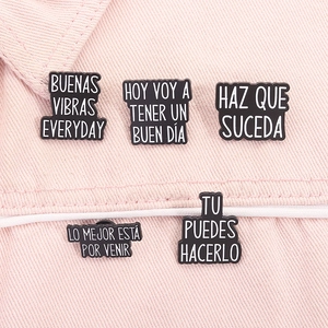 Detailed view of Spanish inspirational enamel pins on pink denim fabric texture