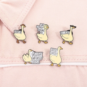 Detail of five funny white goose enamel pins with humorous slogans on pink denim fabric