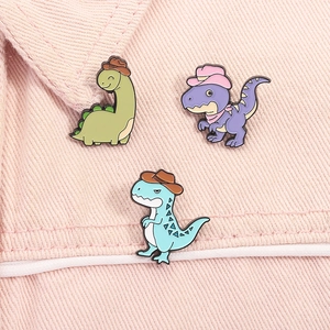 Dettaglio di spille in smalto con dinosauri carini su sfondo di tessuto denim rosa