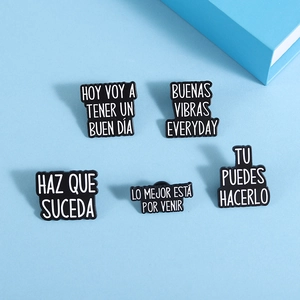 Close-up of five black enamel pins with Spanish phrases on light blue background
