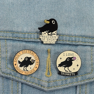 Three-piece black crow enamel pin set featuring shiny trinkets on denim jacket