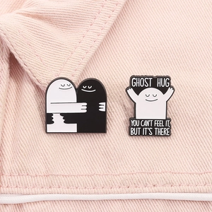 Detail van zwart-witte Ghost Hug emaille pins op zachtroze stoffen achtergrond