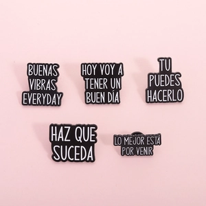 Set of five black enamel pins with Spanish motivational quotes on pink background