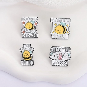 Set of four cute enamel bee pins with motivational puns on a white display tray