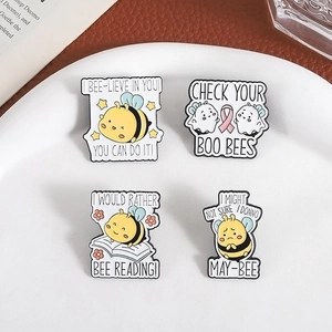 Set of four cute cartoon bee enamel pins with motivational quotes on a white plate