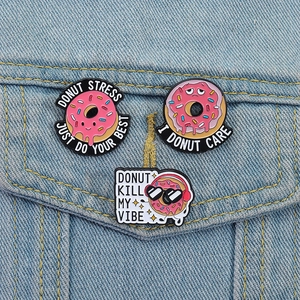 Set di tre spille smaltate a forma di ciambella rosa su giacca di jeans