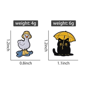 Detail view of cartoon enamel pins showing exact size and weight of cat and goose designs