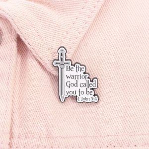 Close-up of sword-shaped enamel pin with motivational quote on pink denim collar