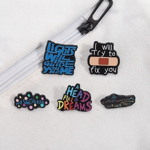 Detailed view of five enamel pins with lyrics on white canvas background