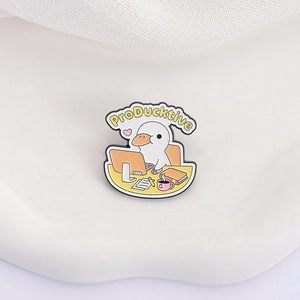 Cute ProDucktive enamel pin featuring a cartoon white duck working at a desk on white background