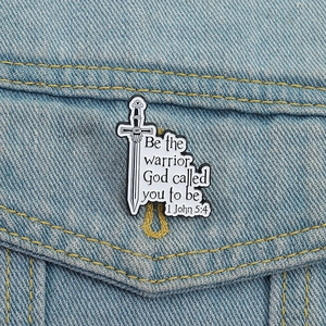 Vintage sword enamel pin with warrior motivational text on denim jacket pocket