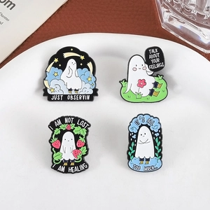 Set of four cute white ghost enamel pins with emotional quotes on a white ceramic plate