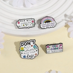 Set of four colorful enamel pins with floral and rainbow designs on a textured surface